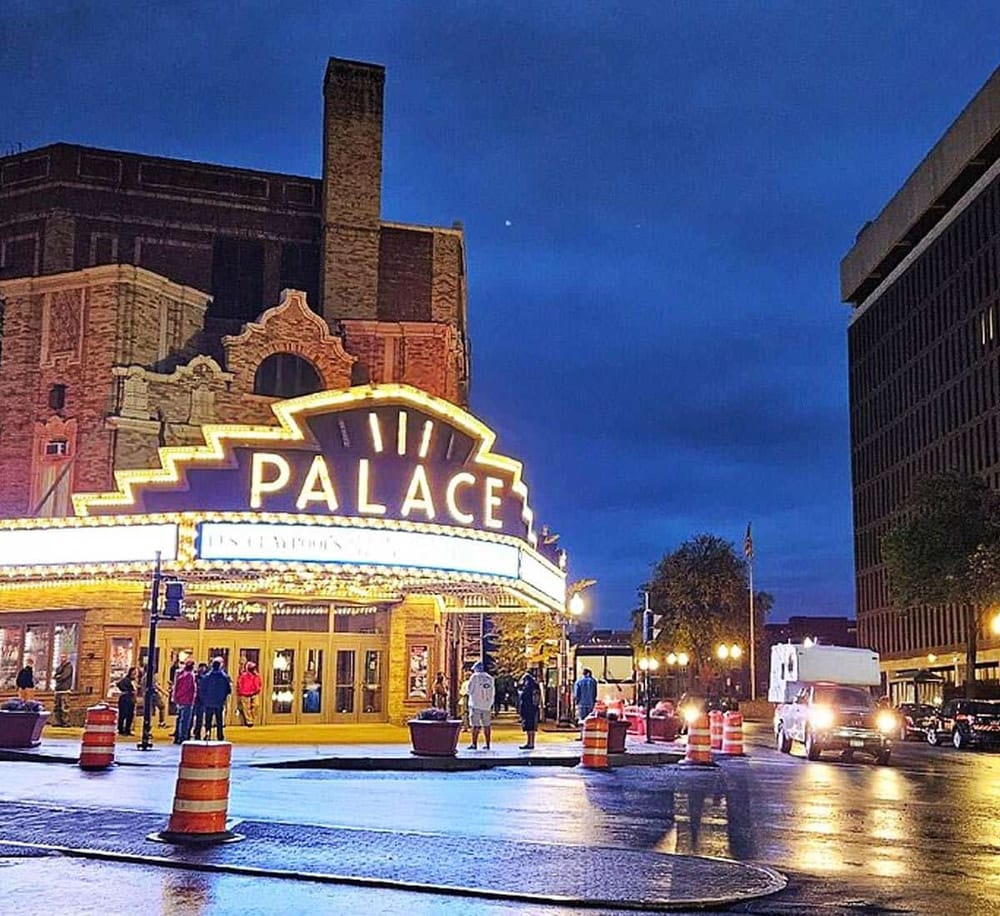 Brightly lit Palace Theater marquee at night in downtown city.
