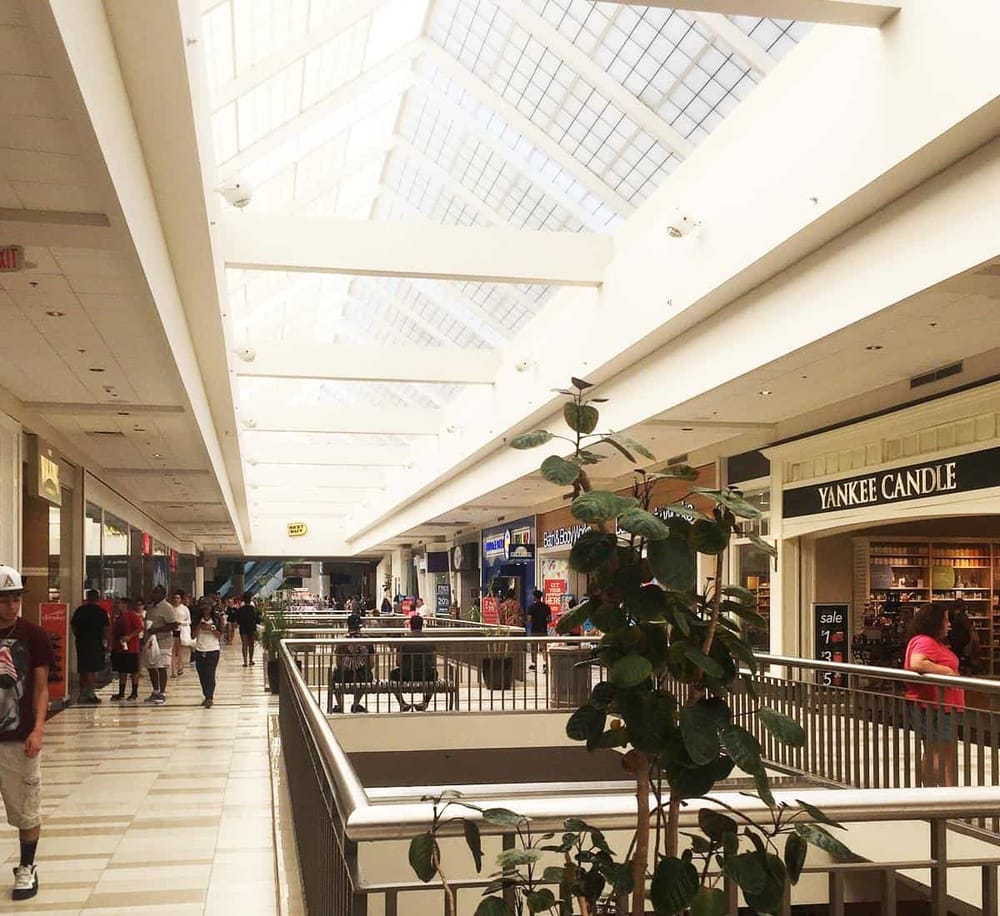 Bright indoor shopping mall with skylight ceiling and retail stores.