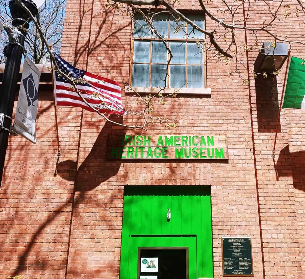 Colorful Irish American Heritage Museum on brick building with flags and green sign.