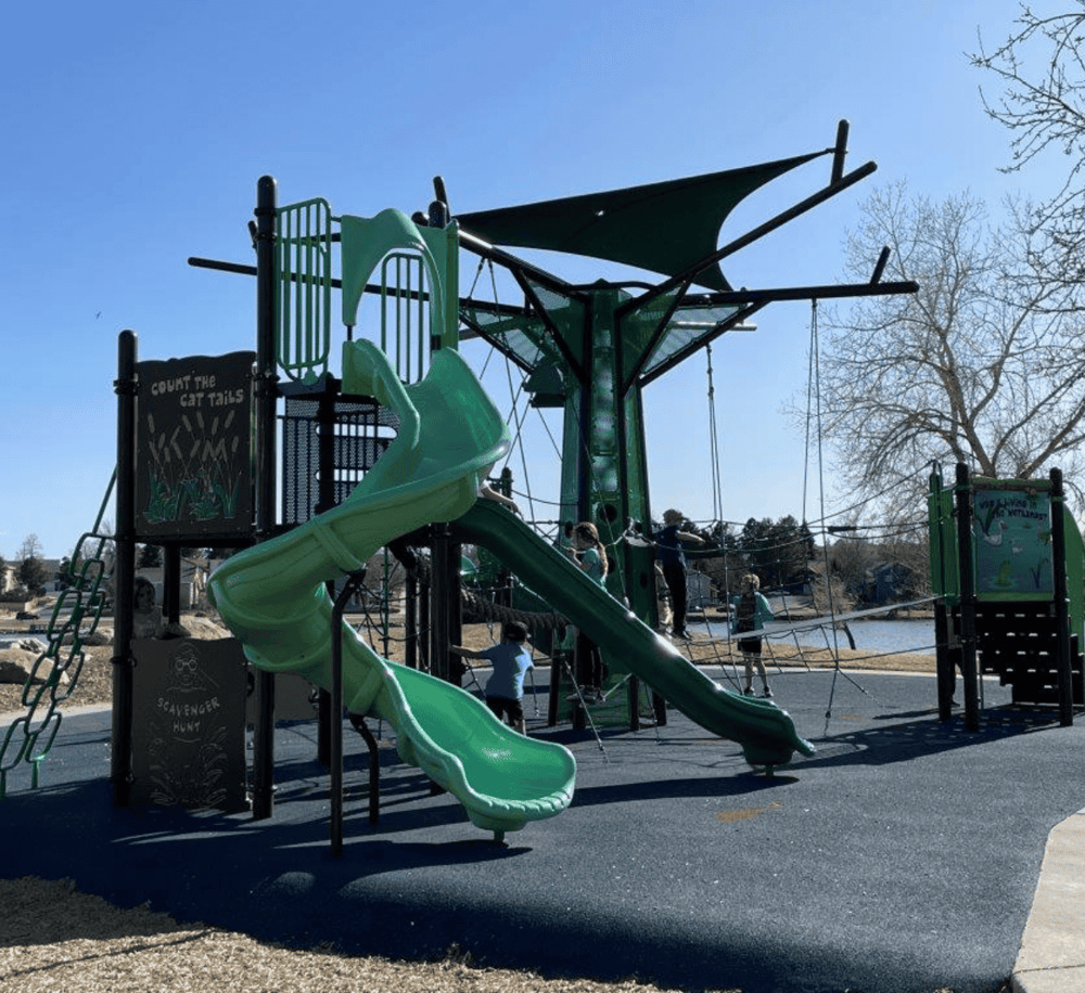 Bright green playground slide at outdoor park, family and kids enjoying play area.