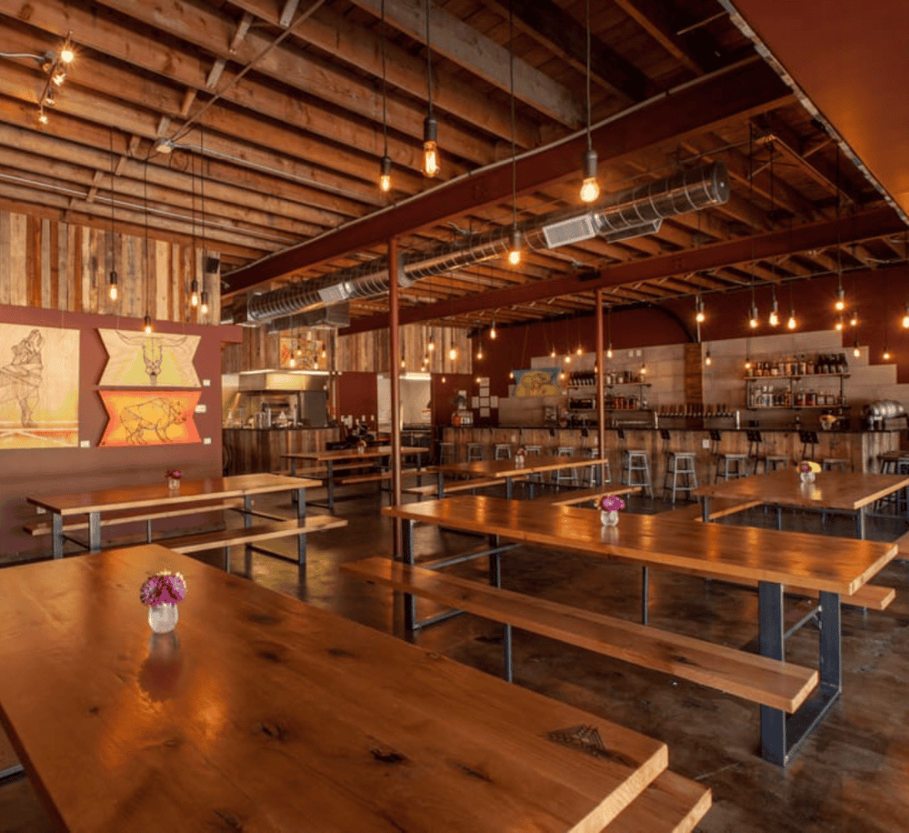 Cozy rustic restaurant interior with wooden tables, ambient lighting, and modern decor, perfect for dining and socializing.