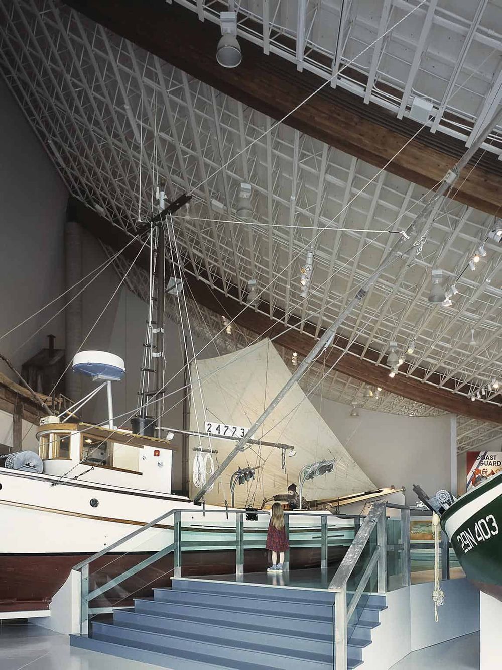 Historic maritime ship displayed in a museum with high ceiling and industrial design elements.