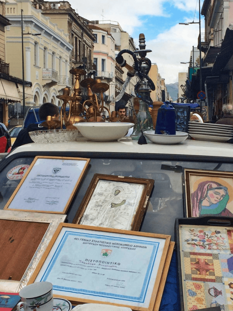 Antique market street with vintage items for sale, sidewalk displays, and city architecture.