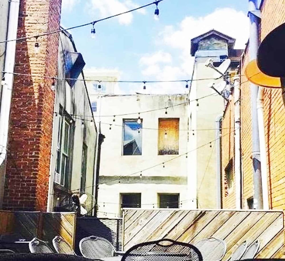 Colorful city alleyway with string lights and patio seating for outdoor dining.
