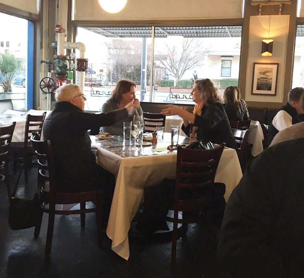 Older woman and middle-aged woman having a conversation at a restaurant table.