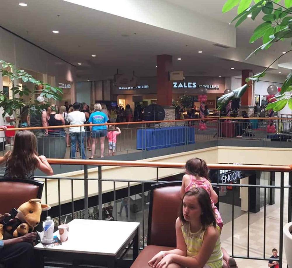 Crowded shopping mall with Quest for Directions and Zales Jewelry stores in the background.