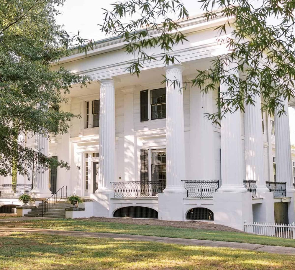 Elegant white historic mansion with tall columns and classic architecture.