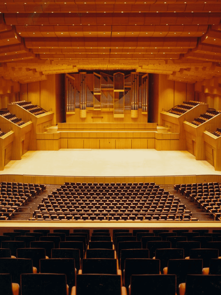 Modern concert hall with wooden interior and grand stage, perfect for music and performances.