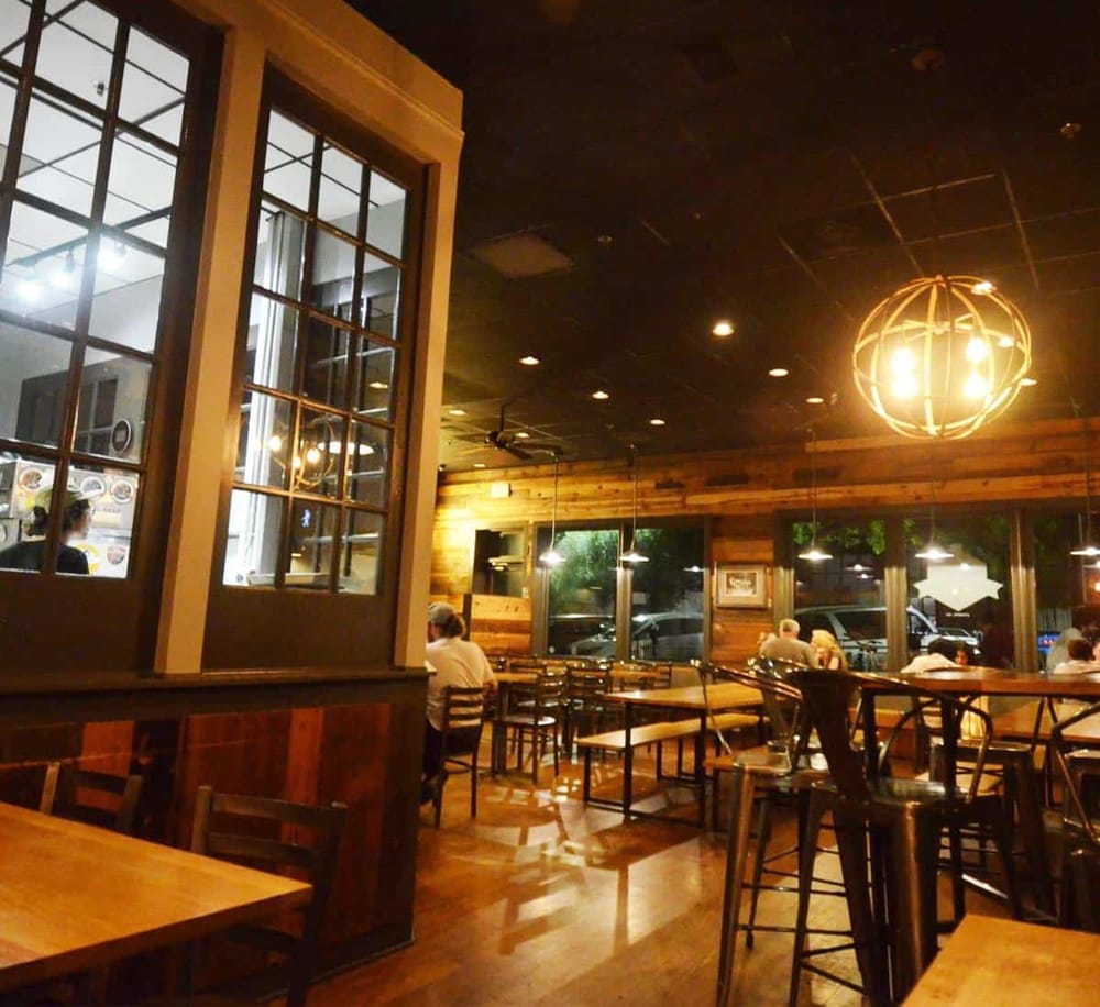 Cozy restaurant interior with wooden accents, warm lighting, and large windows, perfect for dining out.