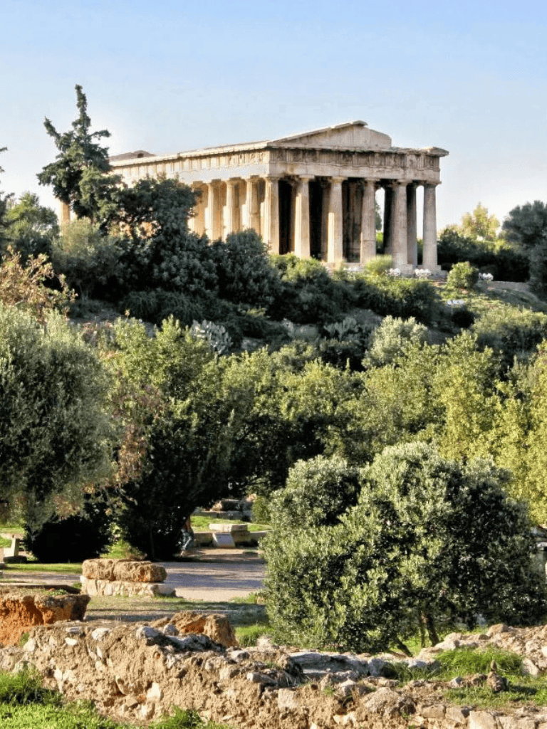 Ancient Greek Parthenon atop Athens hill surrounded by lush greenery and trees.