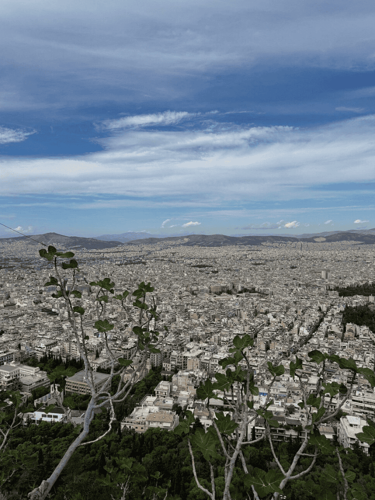 Panoramic view of Athens, Greece, from Lycabettus Hill, showcasing the city's skyline and Acropolis in the distance.