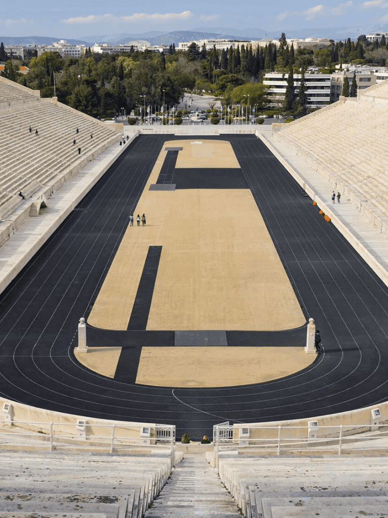 Track and field stadium with running track and seating area, outdoors during daytime.