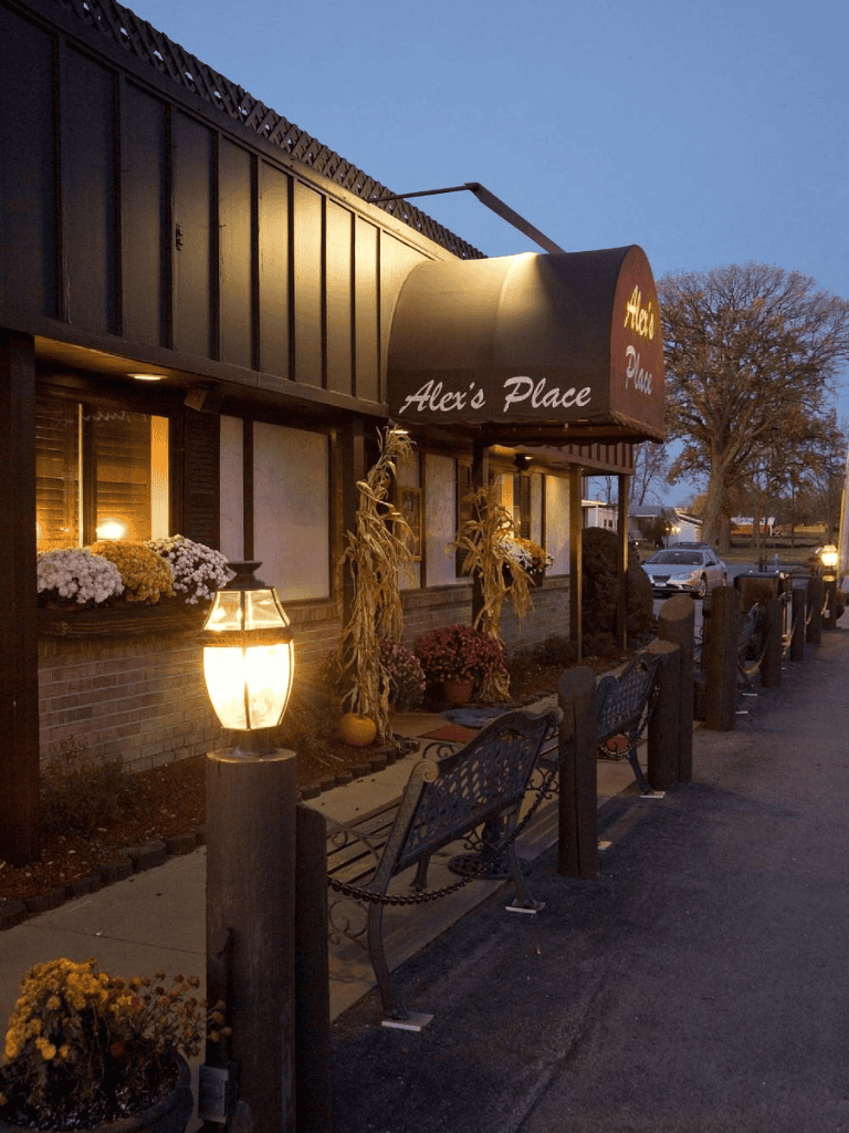 Cozy restaurant storefront with autumn decorations during evening hours, inviting dining experience.