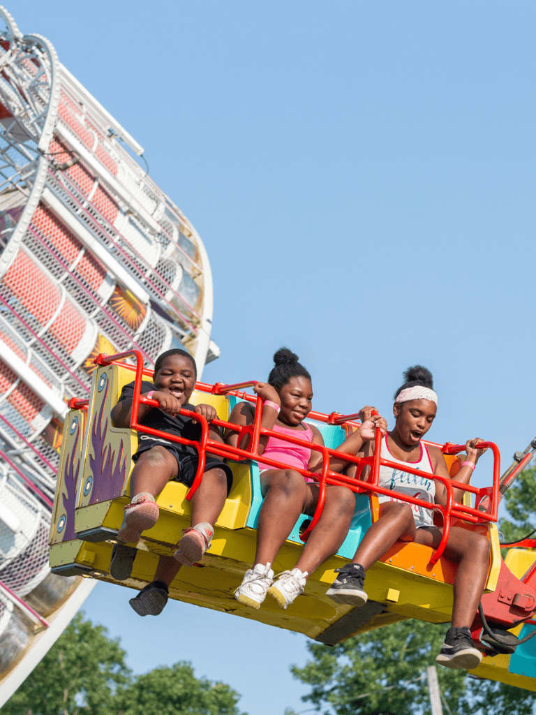 Thrilling amusement park ride with children enjoying a ferris wheel in bright daylight.