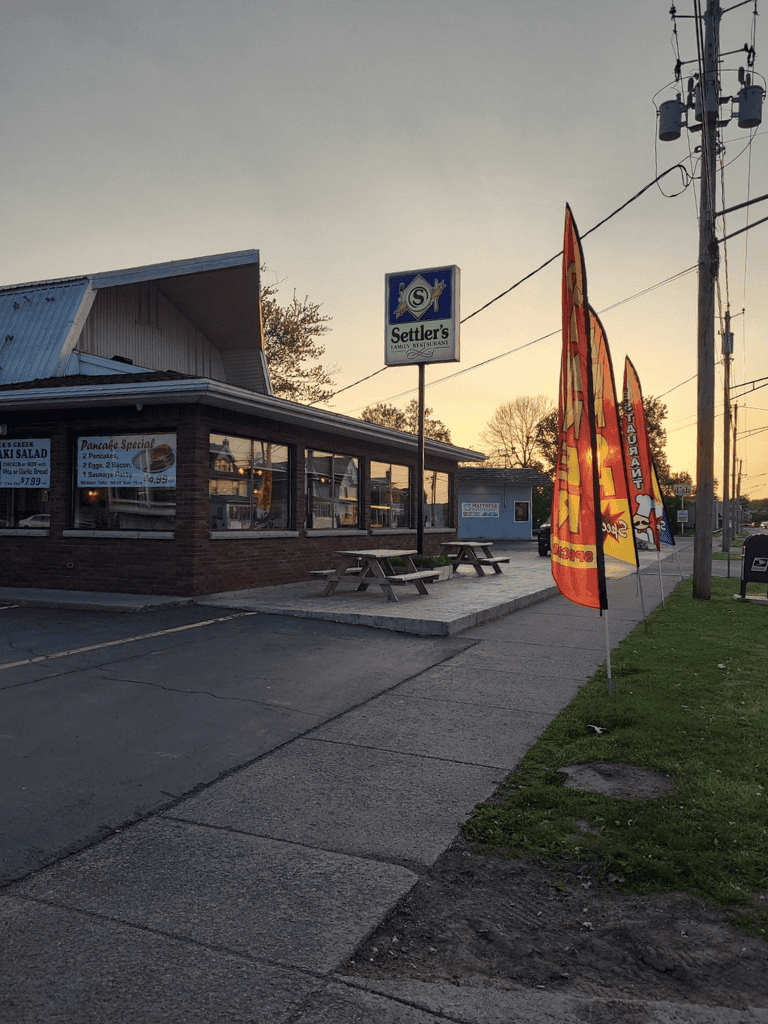 1. Family restaurant with outdoor seating and flags at sunset.