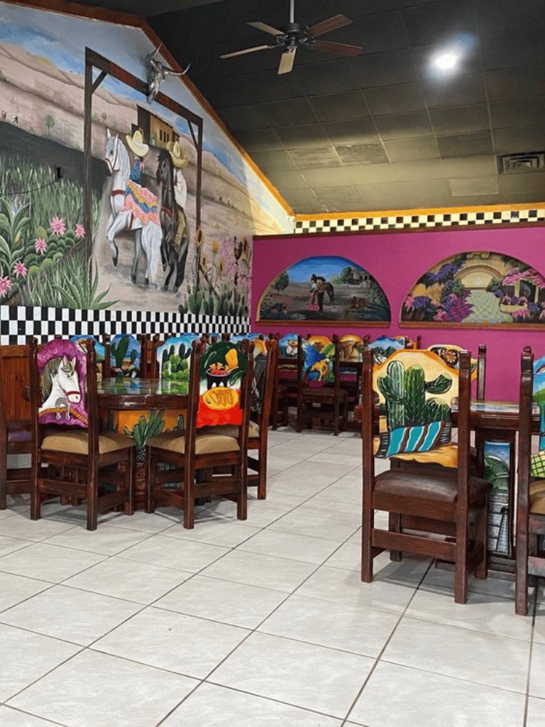 Colorful themed restaurant with vibrant murals and painted chairs, showcasing a lively atmosphere for dining.