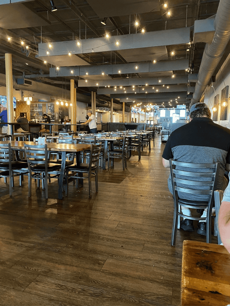 Spacious modern restaurant interior with wooden tables, stylish decor, and ambient lighting.