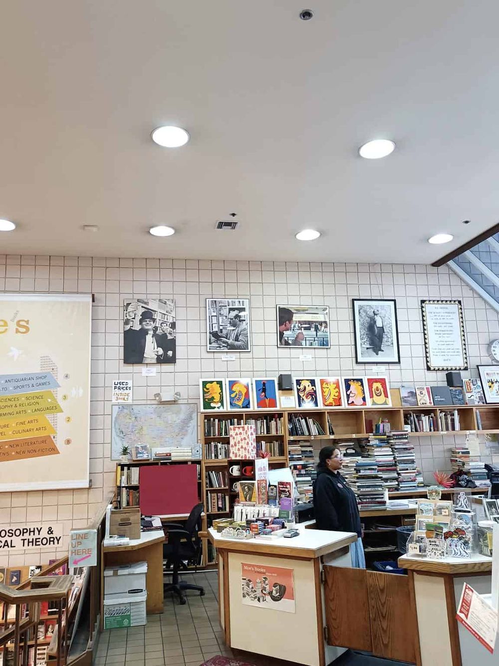 Cozy bookstore interior with shelves of books, artwork, and a staff member assisting customers, ideal for book lovers and exploration.