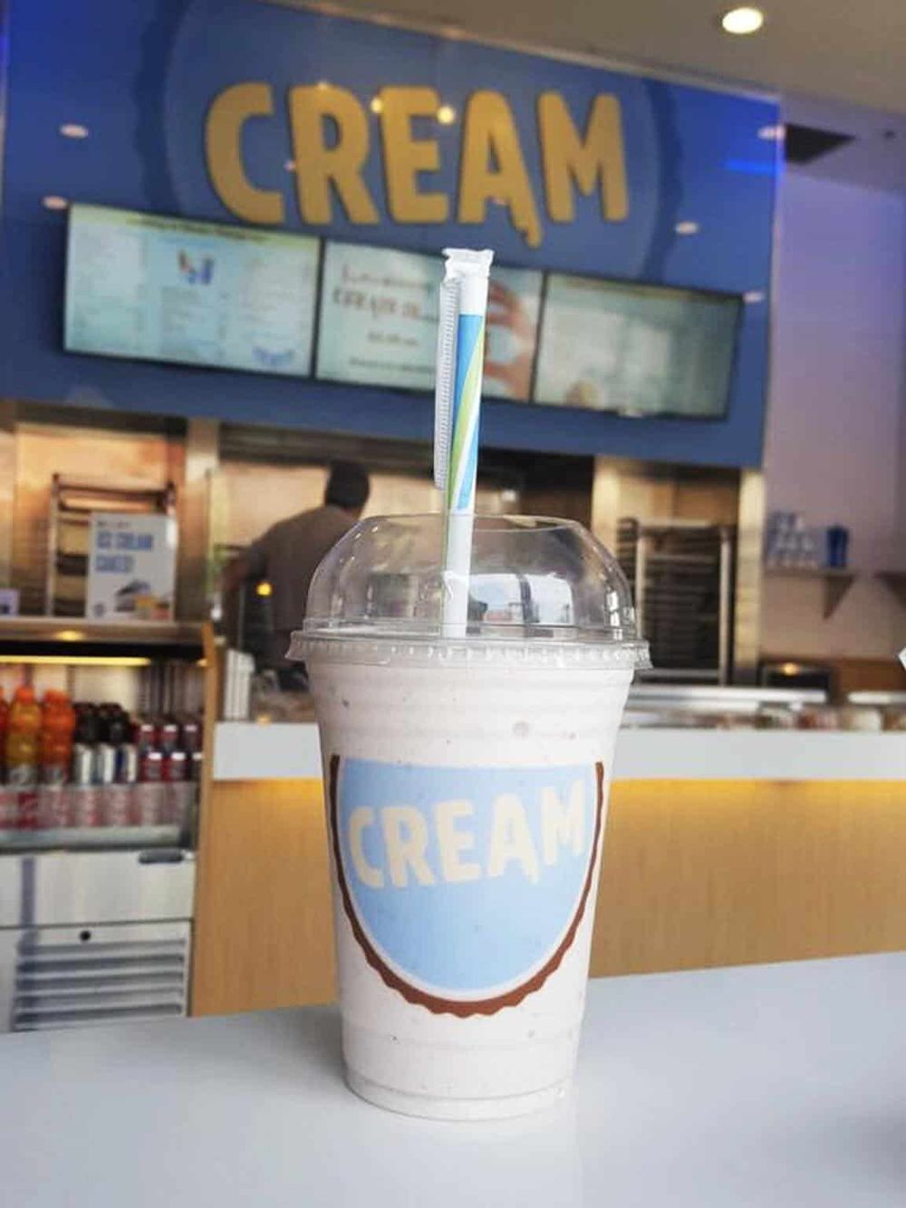 Refreshing vanilla milkshake in a clear cup with a colorful striped straw at Quest for Directions ice cream shop.