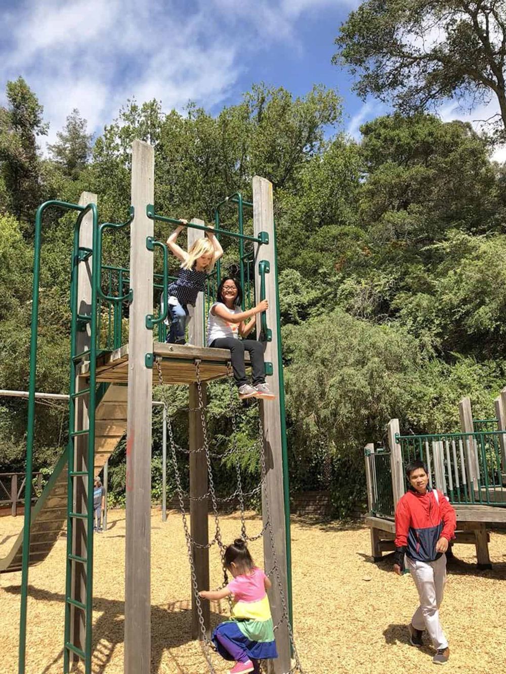 Kids playing on outdoor playground equipment in a park, enjoying fun and active outdoor family activities.