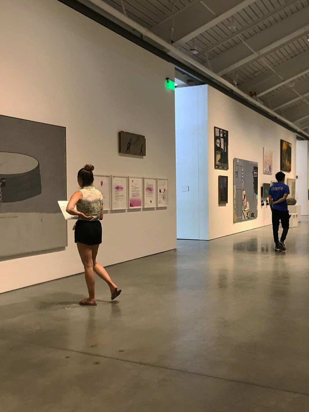 Modern art gallery with visitors viewing contemporary artworks and sculptures.