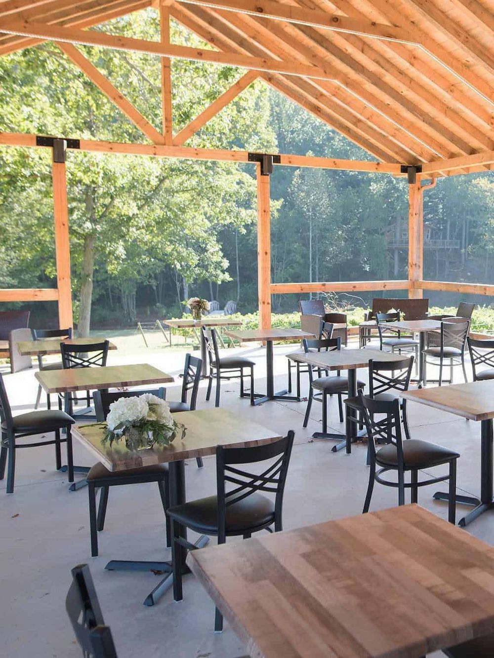 1. Modern outdoor dining area with wooden beams and lush green background.