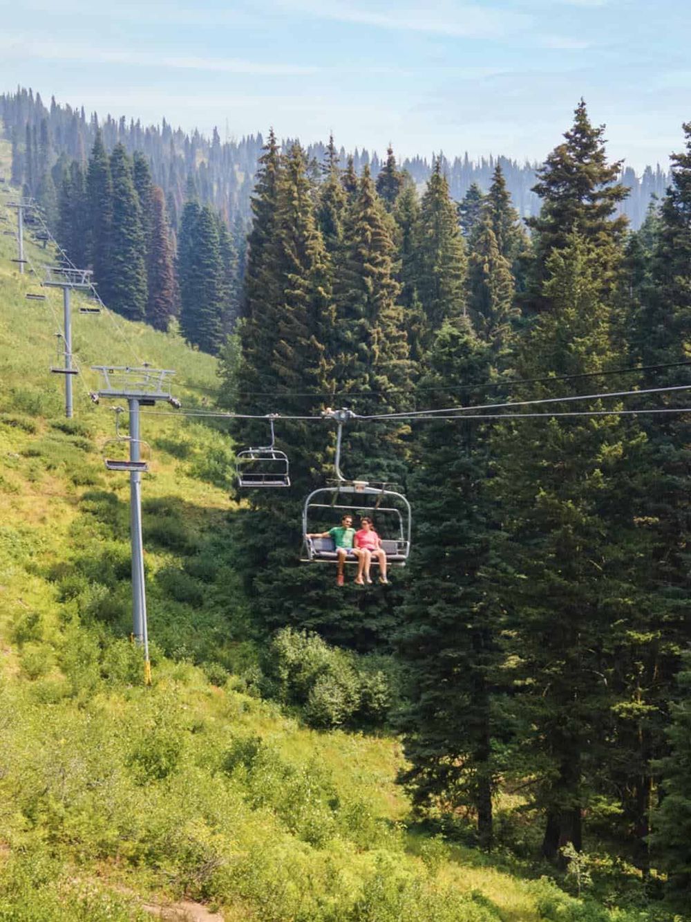Vibrant mountain landscape with a scenic chairlift ride through lush green pine forest.