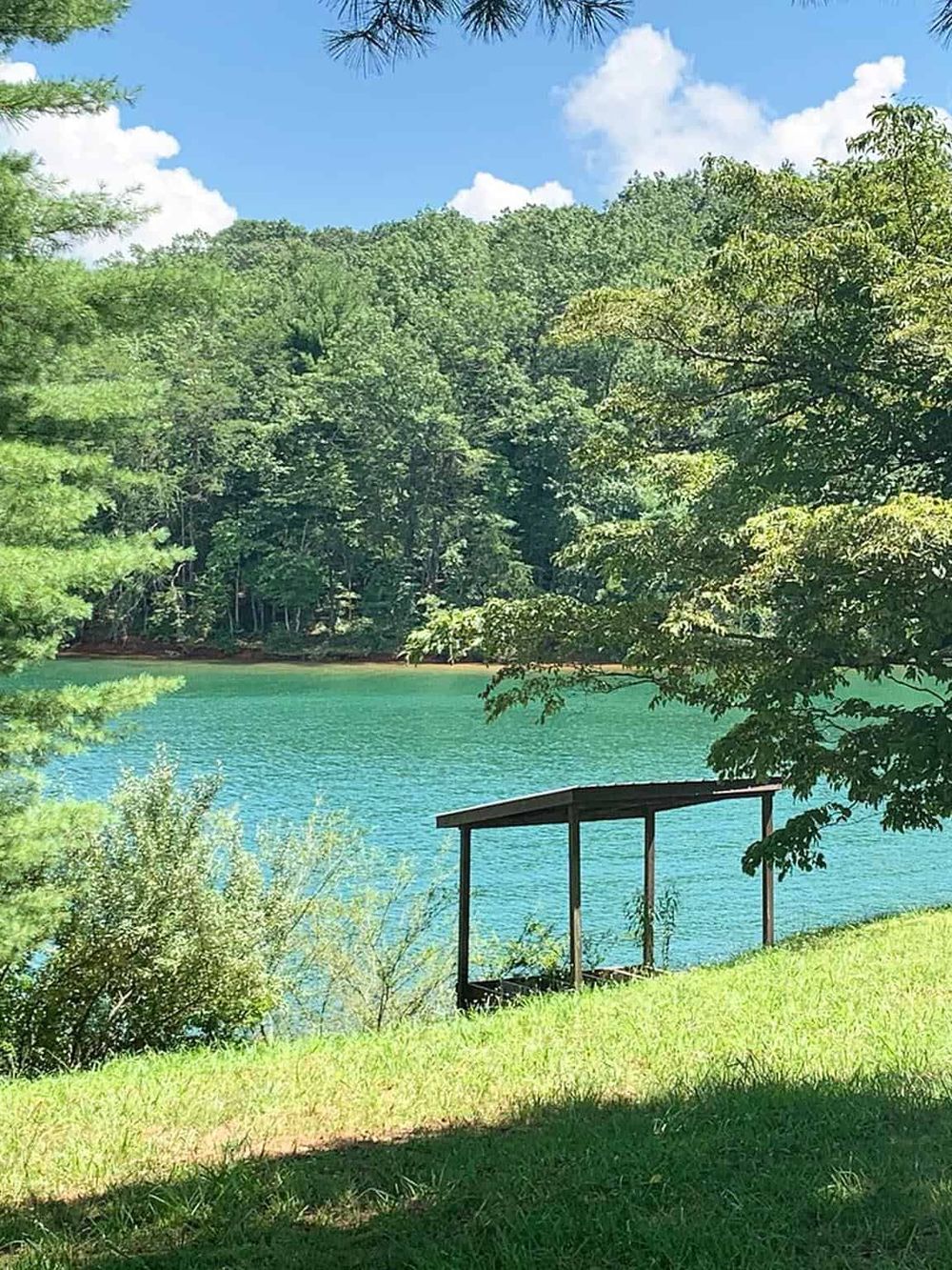 Serene lakeside scene in Blue Ridge, Georgia with lush greenery, clear water, and a peaceful shelter by the water's edge.