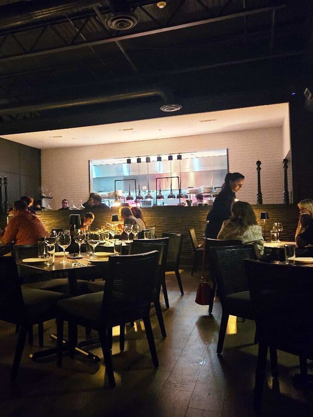 Elegant restaurant interior with dim lighting and a modern open kitchen setting.