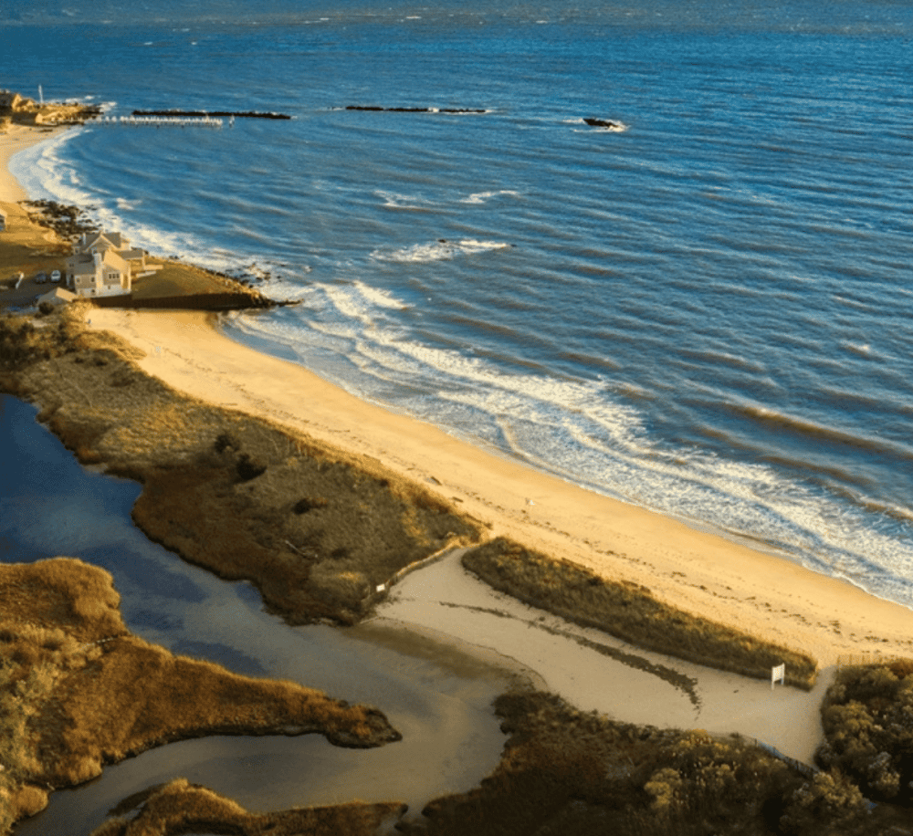 Seaside beach with gentle waves and coastal homes, perfect for travel and adventure planning.