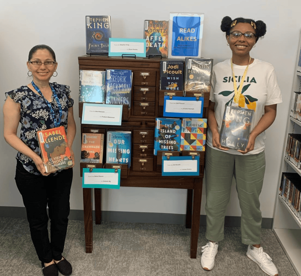 A diverse group of women showcasing new books at a library event for promoting reading and literacy.