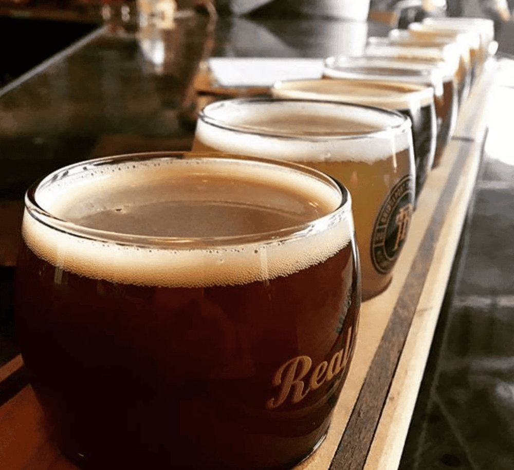 Rich amber craft beers on a bar counter with foam head, showcasing artisanal brewing.