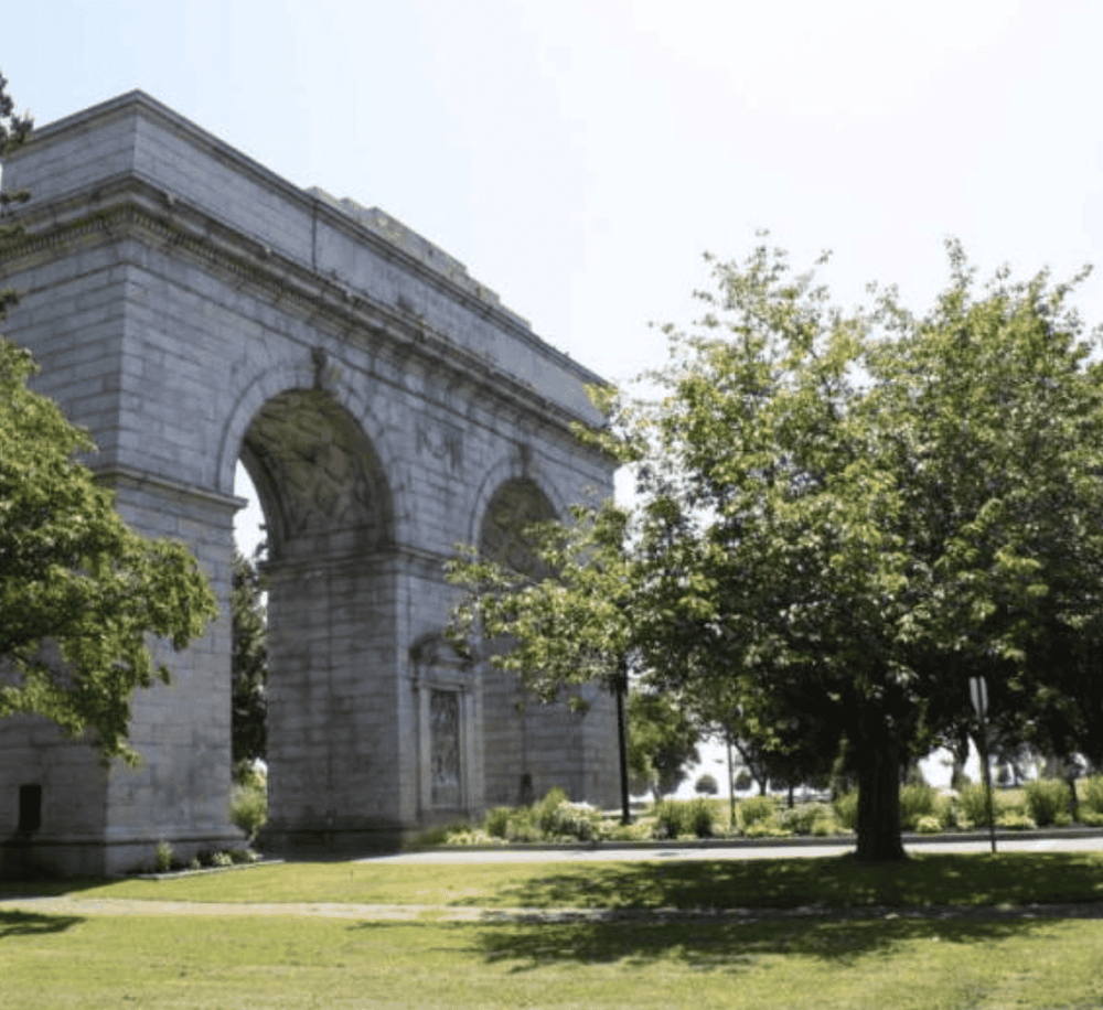 Arlington Memorial Arc de Triomphe in a park with green trees and grass, showcasing a historic monument.