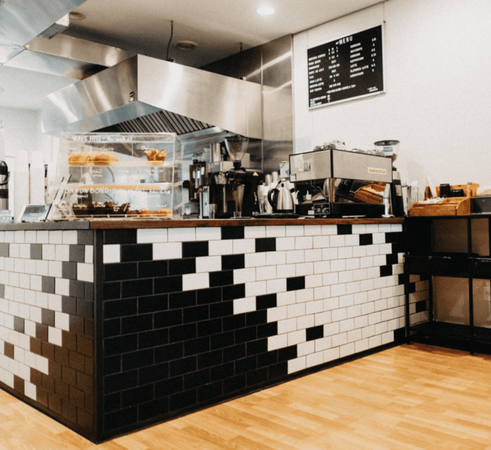 Cold brew coffee counter at QuestForDirections cafe, modern black-and-white tiled design.