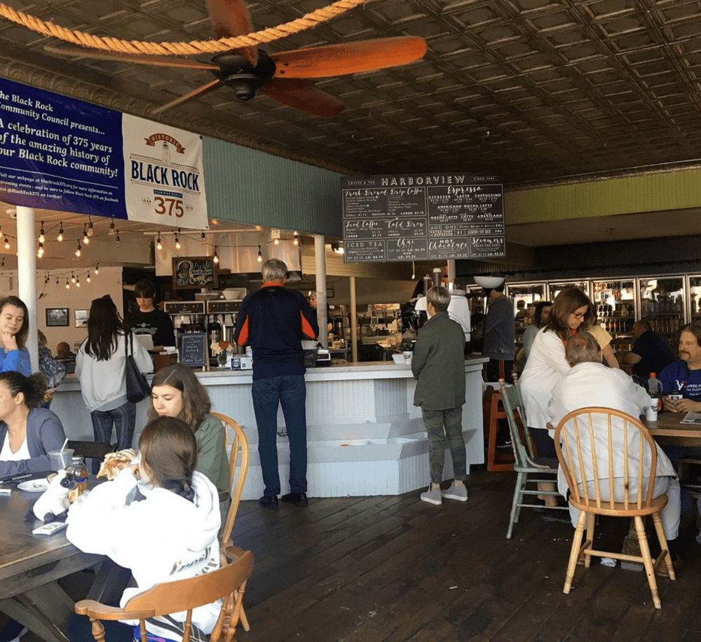 Cozy indoor café with people enjoying meals and drinks, rustic decor, and a welcoming ambiance for diners.