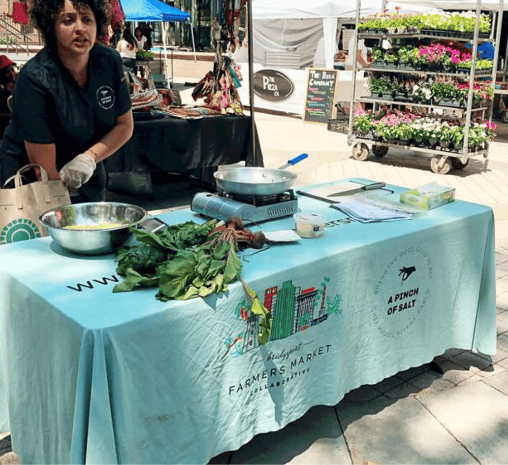 Fresh farm herbs and cooking demo at farmers market for healthy living and local food advocacy.