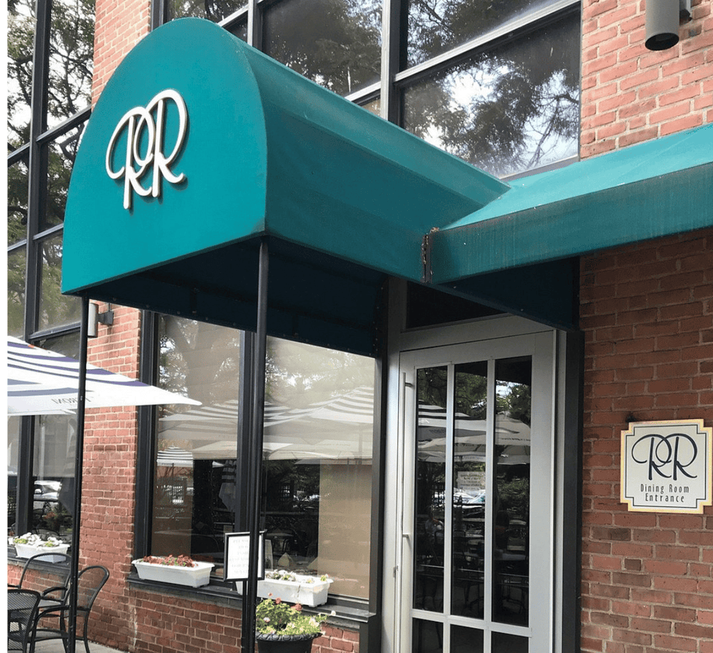 Charming restaurant entrance with teal canopy and "R" logo, inviting dining experience.