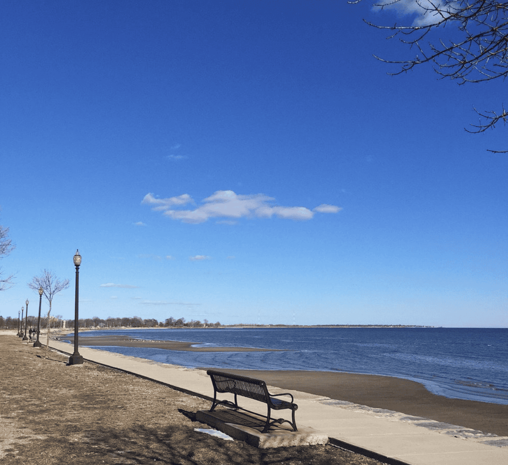 Serene lakeside promenade with benches, lamps, and clear blue sky, perfect for relaxation and scenic views.
