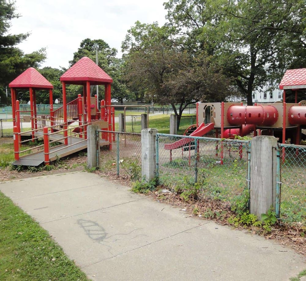 Colorful playground equipment in a park with trees and green space.