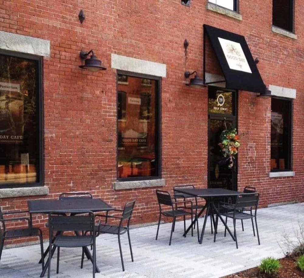 Charming brick café exterior with outdoor seating and floral decor, ideal for enjoying coffee and food.