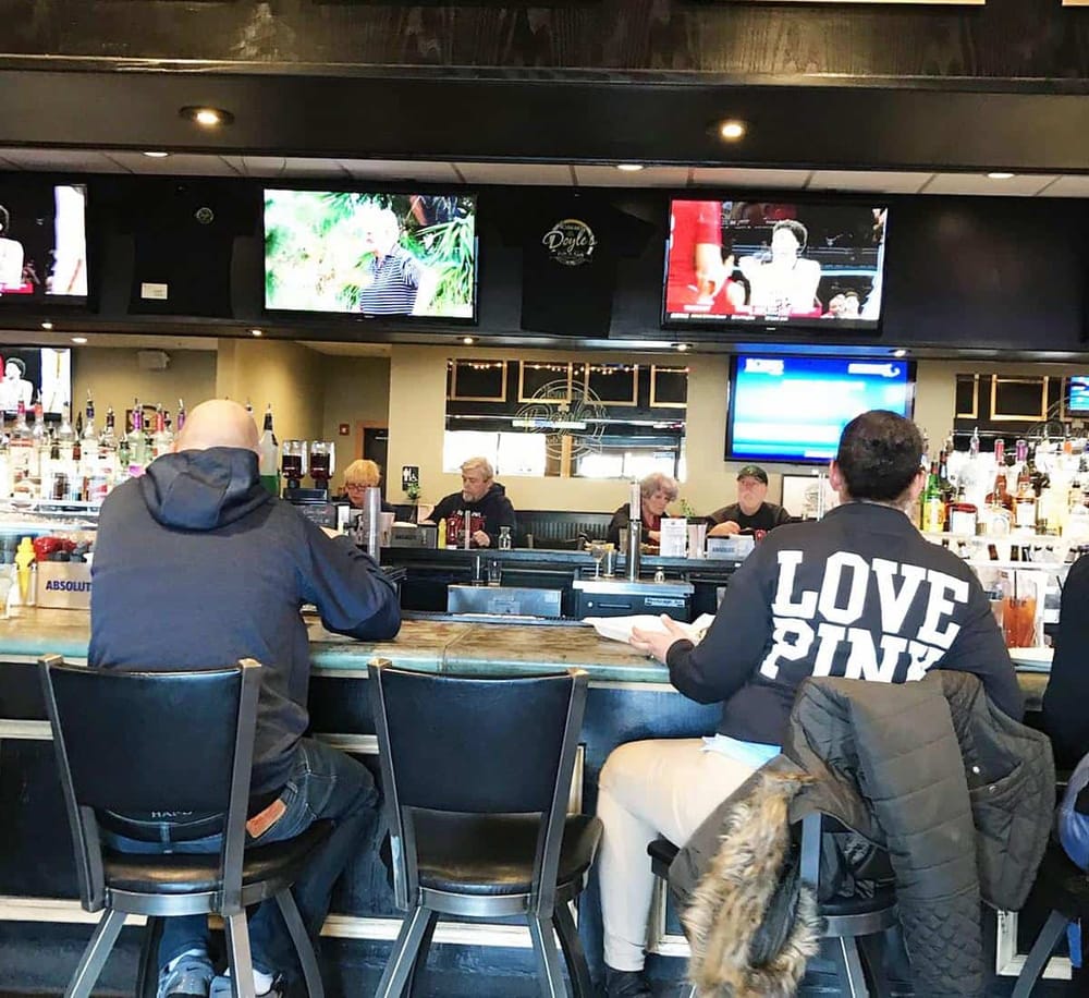 Relaxed sports bar with multiple TVs, bartenders, and customers enjoying drinks and conversations.