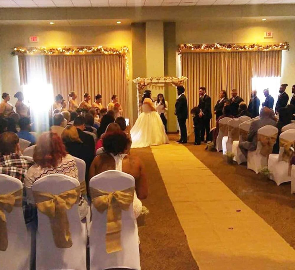 Elegant wedding ceremony with bride and groom exchanging vows in a decorated indoor venue with seated guests.