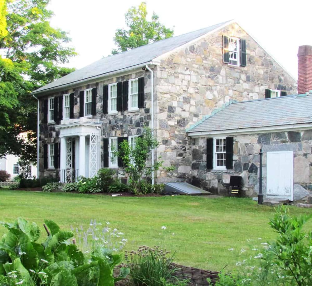 1. Classic stone house with lush green lawn and black shutter windows.