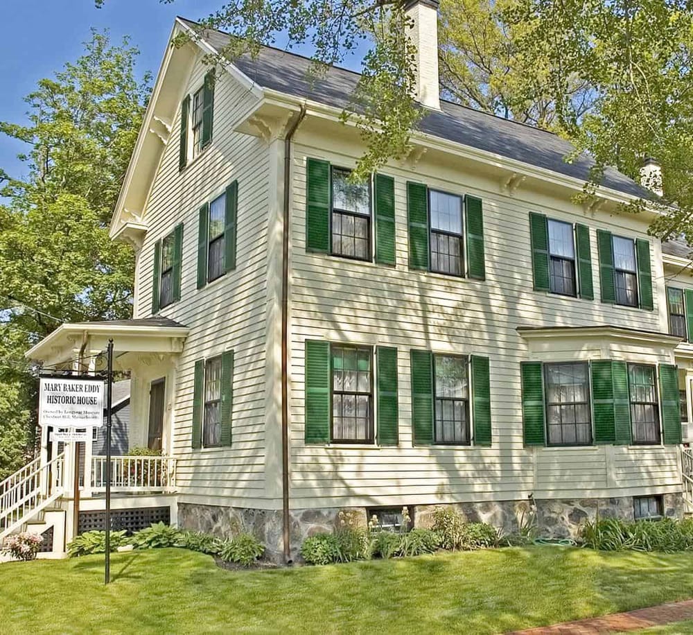 Victorian historic house with green shutters in a lush garden, part of Quest For Directions' local history tour.