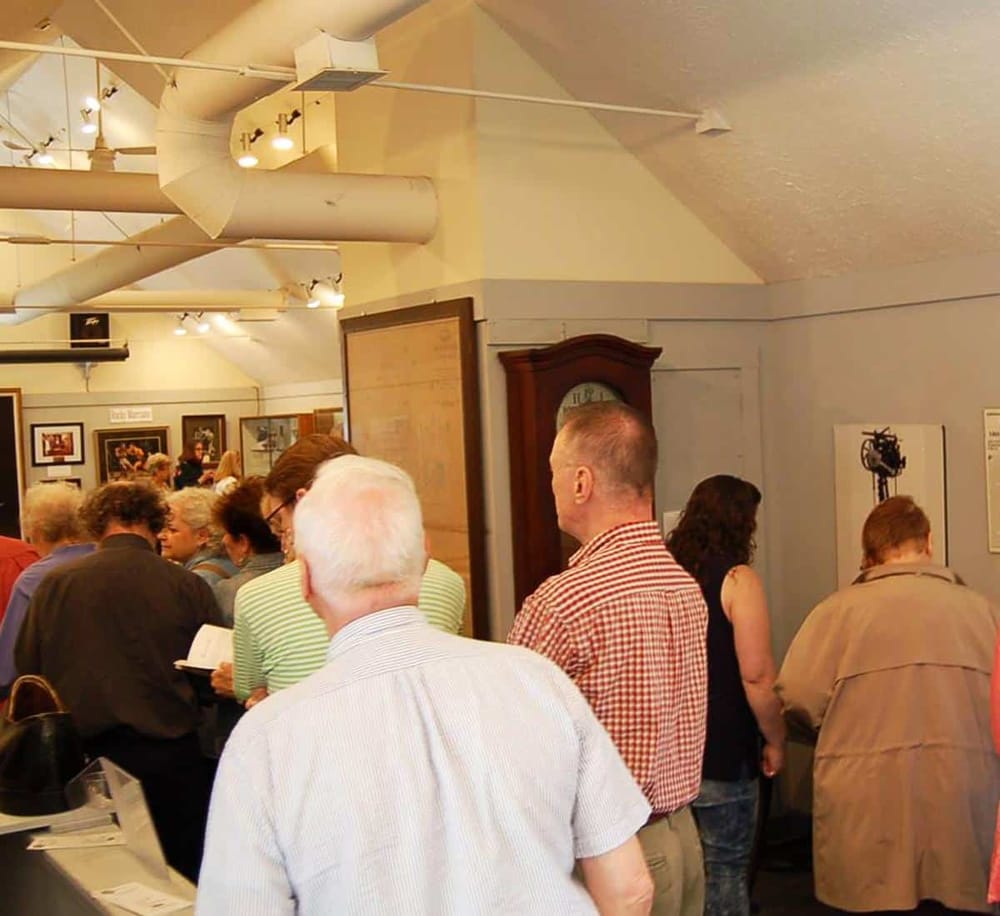 Busy crowd at QuestForDirections community event with people engaging in discussions and viewing displays.