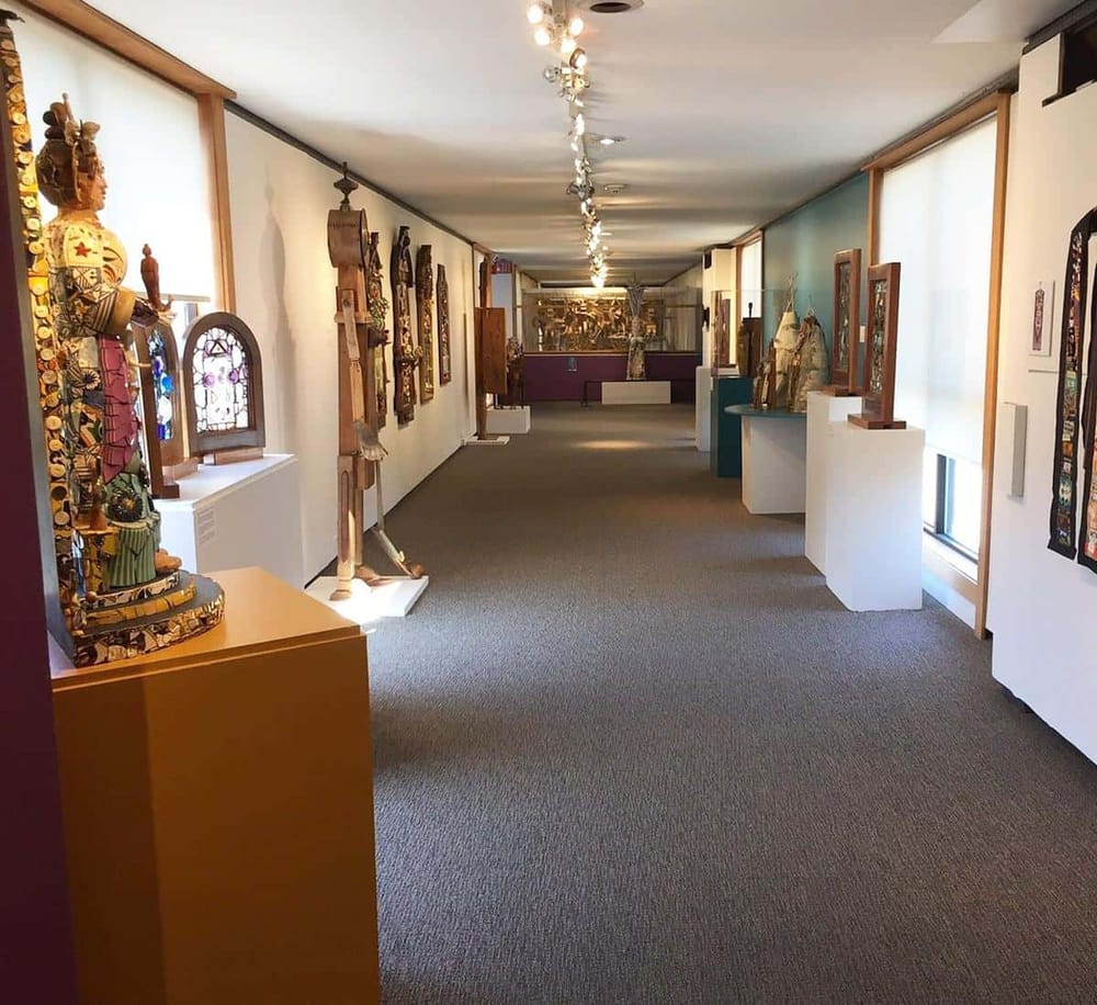 Colorful tribal art and sculptures displayed in an elegant museum gallery with natural lighting.