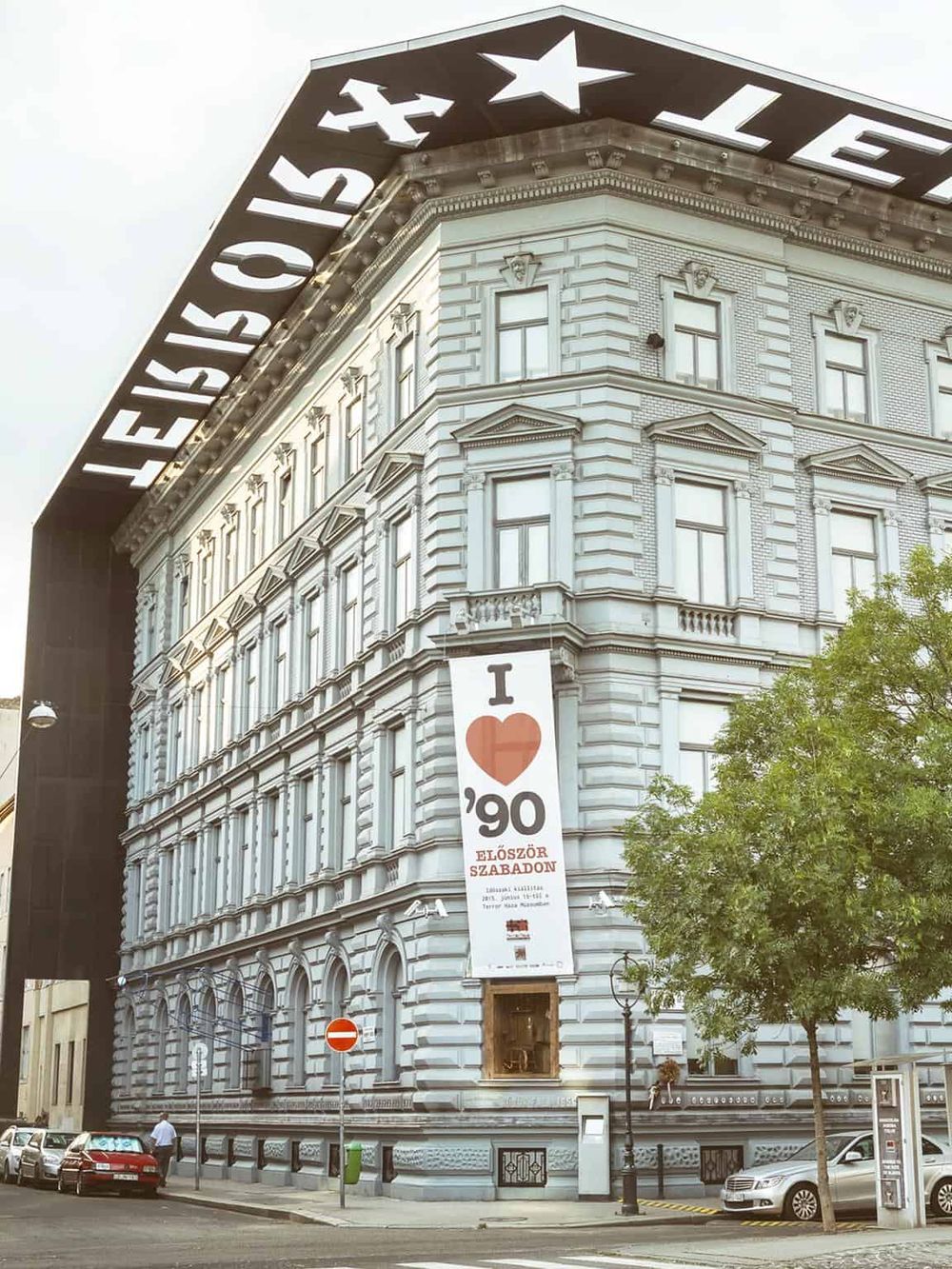 Historic building in Budapest with "I love '90" banner celebrating Hungarian history and culture.