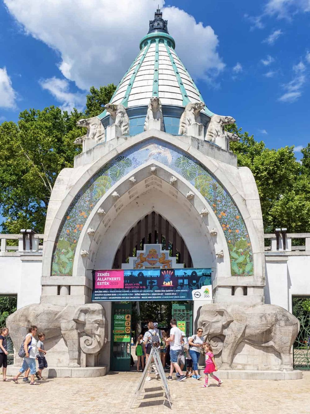 Colorful zoo entrance with animal sculptures and visitors, showcasing Budapest Zoo's architectural design.