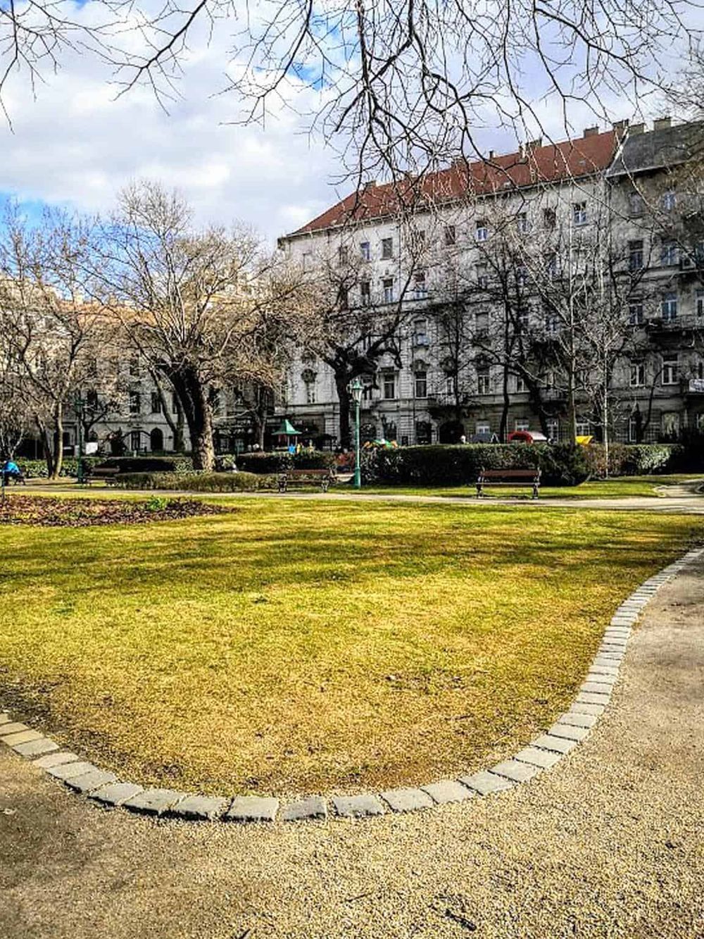 Quiet city park with trees and benches, central location for navigation and directions.