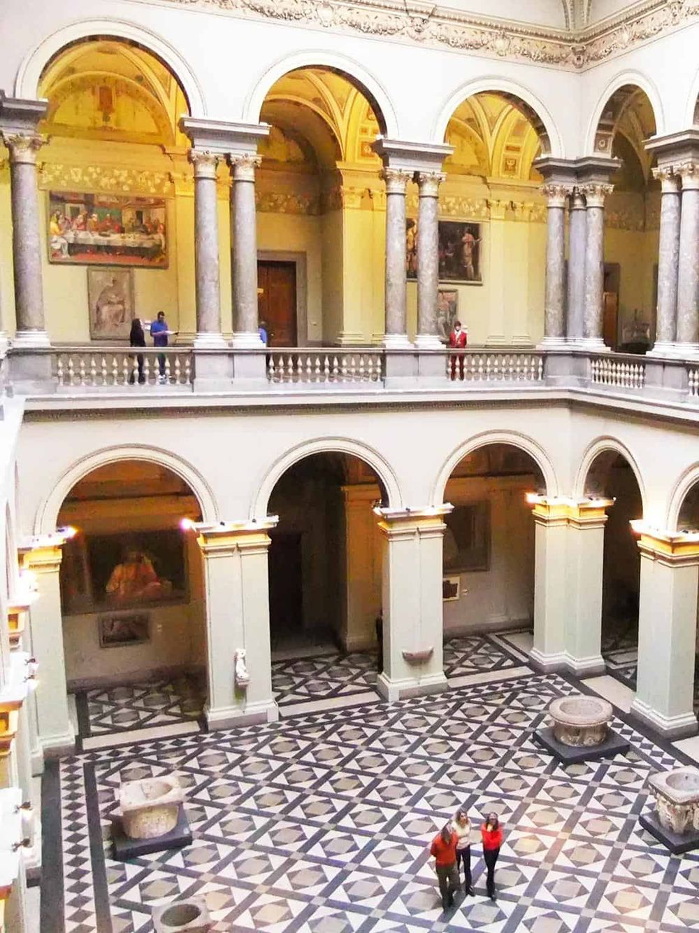 Luxurious historical museum interior with grand arches, marble columns, classic paintings, and ornate design elements.
